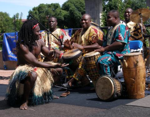 3 persons playing drums and 1 dancer