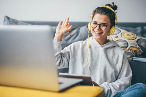 Student raises hand in front of computer